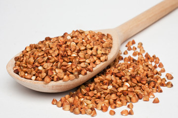 Buckwheat with a wooden spoon on a white background