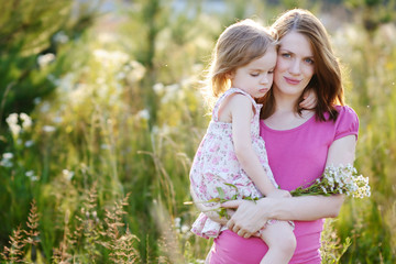 Young mother and her little girl in a meadow