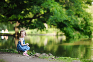 Adorable little girl sitting by the water