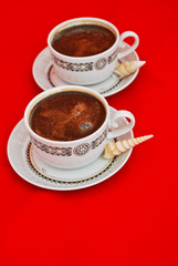 Two cups of coffee and seashells isolated on red