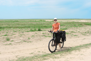 bicycle tourist girl standing on road, blue sky and horizon