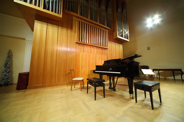 Massive wooden pipe organ and black concert grand piano