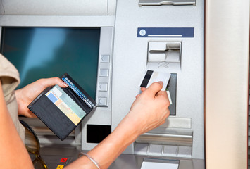 Cash withdrawal. Woman's hand inserting plastic card Visa