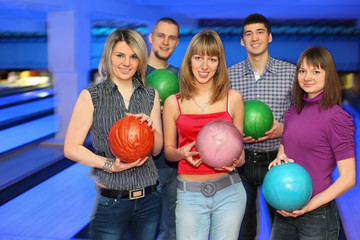 Fototapeta na wymiar Five friends stand alongside and holds balls for bowling