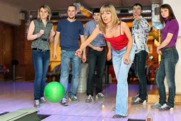 Girl throw ball on lane for bowling, friends worry for results