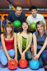 Three girlfriends squatting and behind stands two fellows  and e