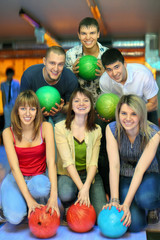 Girls of squatting and fellows  back stand with ball for bowling