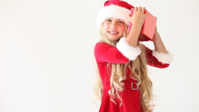 little miss santa shaking and opening a gift, smiling