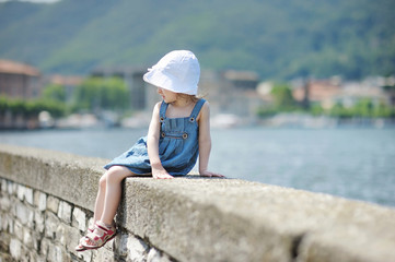 Little girl sitting on a stone parapet