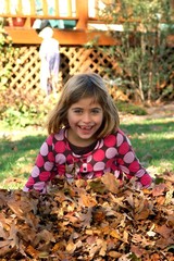 Young girl plays in a pile of leaves