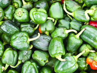 Green bell peppers on a counter in an open marketplace