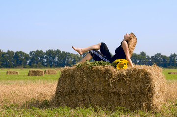 Girl in the field Girl is sitting on sheaf hay at the field