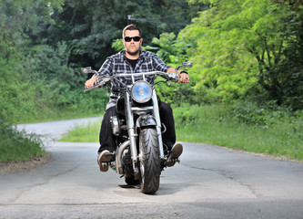 Young man riding a chopper on a road