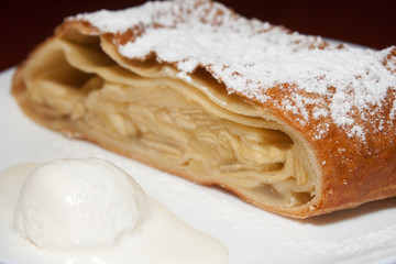 Apple pie with powdered sugar and ice cream at the forefront