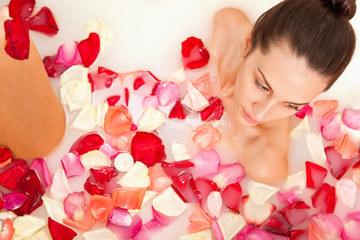 Obraz na płótnie Canvas Attractive naked girl enjoys a bath with milk and rose petals