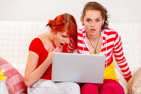 Two girlfriends amazed the seen in a laptop