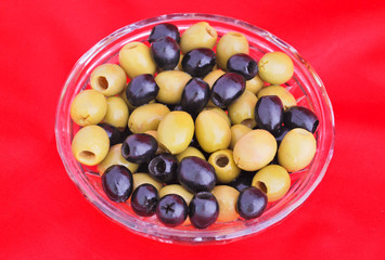 Black and green olives in a crystal bowl isolated on red