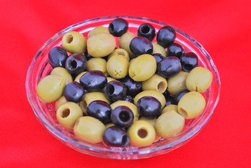 Black and green olives in a crystal bowl isolated on red