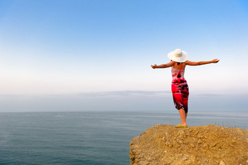 The woman on a mountain with open hands, against the blue sky