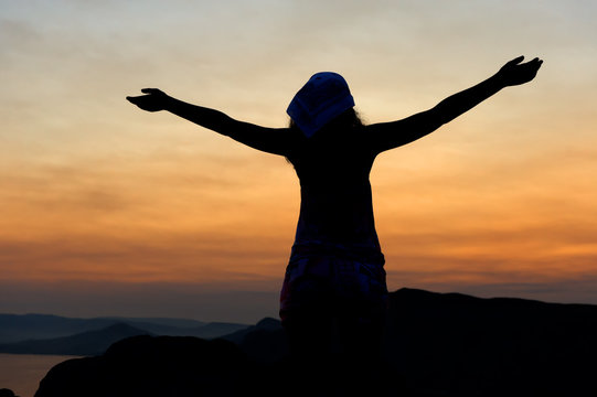 The woman on a mountain with open hands welcomes a decline.