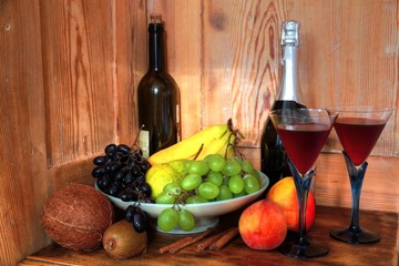 Red wine and fruits on wooden background.