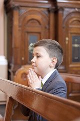 Boy kneeling and praying in the church.