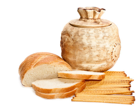 Jug, bread and grain straws on a white background