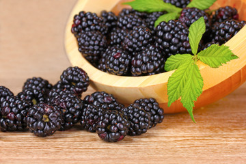 beautiful blackberries in wooden bowl on gray background