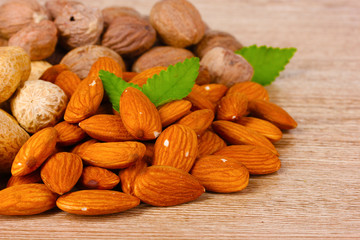 nutmeg, peanuts and almonds on wooden background