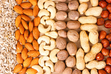 nutmeg, peanuts, hazelnuts and almonds on wooden background