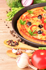 pizza and vegetables on a wooden background