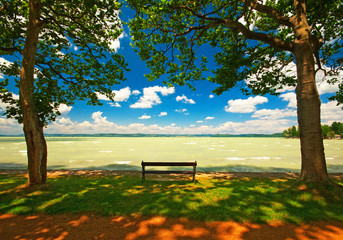 Bench in the park with a nice lake and clouds
