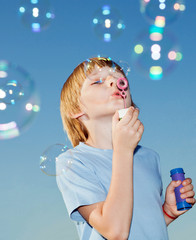 Boy with soap bubbles against a sky