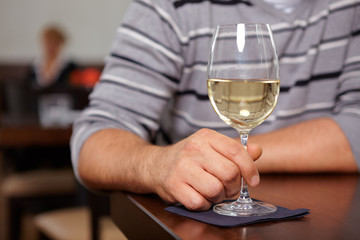 Hand hält Glas mit Weißwein