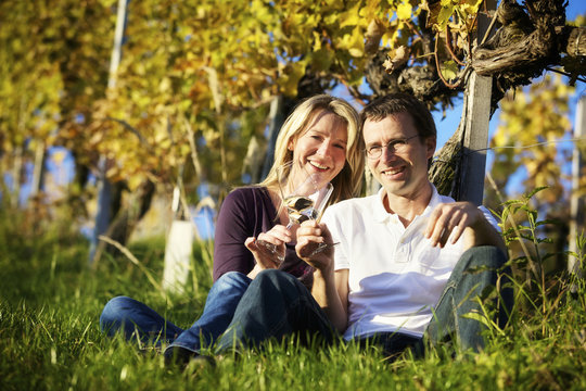 Couple enjoying wine in vineyard.