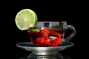 black tea, lime and raspberry in cup on black background