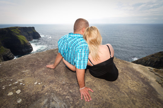 Couple in hug looking to the ocean from Irish cliffs