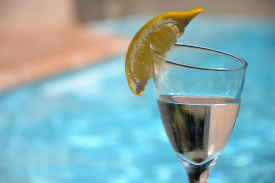 Verre d'eau citronn&eacute;e au bord de la piscine