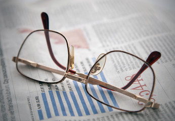 Glasses on a newspaper with financial chart
