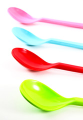 Colorful plastic spoons on white background