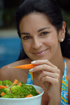 Mujer comiendo ensalada en la piscina.