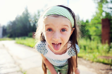 Outdoors portrait of amazed child girl with protruding tongue