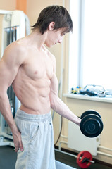 Powerful muscular man lifting weights in gym