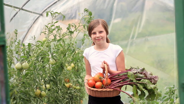 girl holding basket full of fresh vegetables in the garden