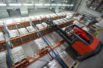 Worker   on   forklift loader loading sacks in warehouse