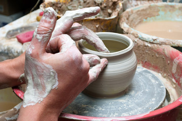 hands of a potter, creating an earthen jar on the circle