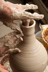hands of a potter, creating an earthen jar on the circle