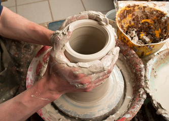 hands of a potter, creating an earthen jar on the circle