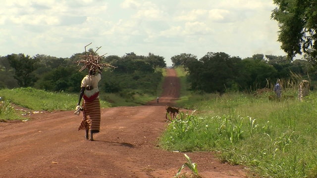 woman walking down dirt road in rural africa