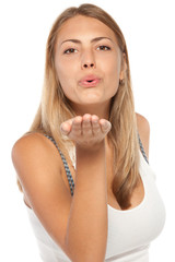 Fototapeta premium Cute young female blowing a kiss at you against white background